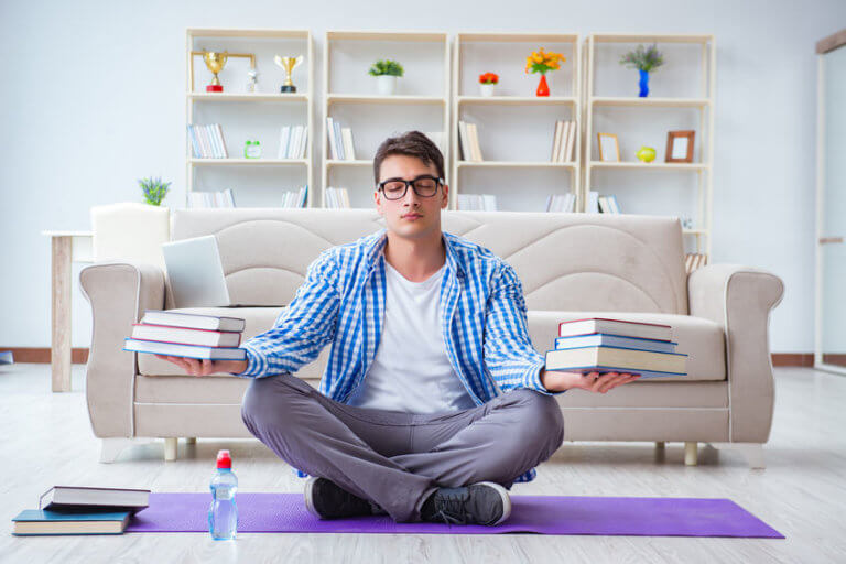 Arbeit, Entspannung und Meditation - ein junger Mann hält Bücher in Balance