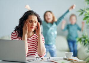Stressmanagement - das Bild zeigt eine Mutter mit Laptop und Kindern
